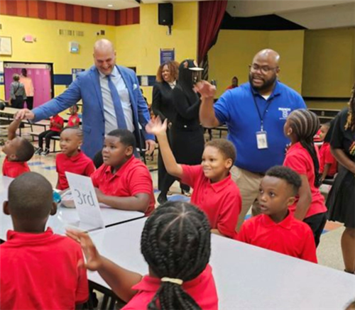 students at table greeting adults